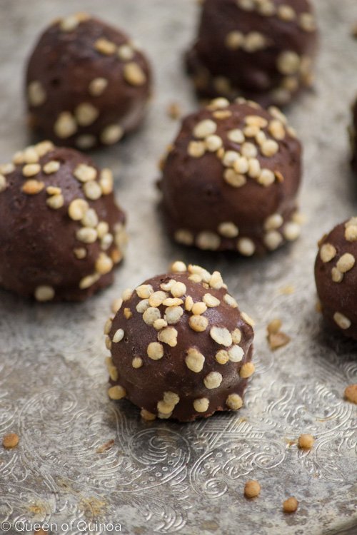 Chocolate covered peanut butter balls on a silver tray. They are covered in nuts.